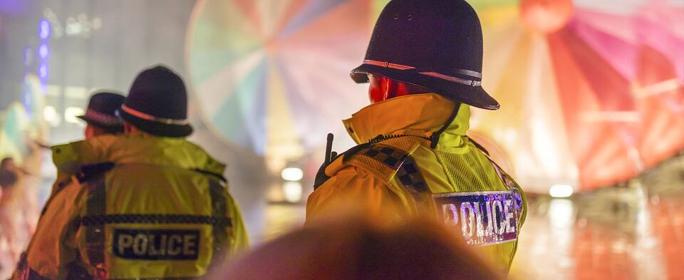 Police officers in high-visibility jackets seen from behind at night